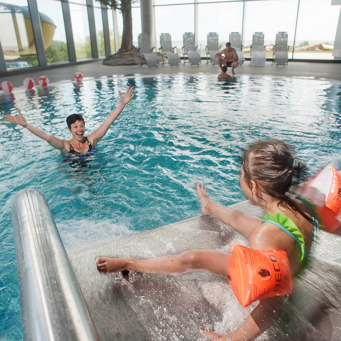 Spaß beim rutschen im Entdeckerbad Ein kleines Mädchen rutscht in die Arme ihrer Mutter