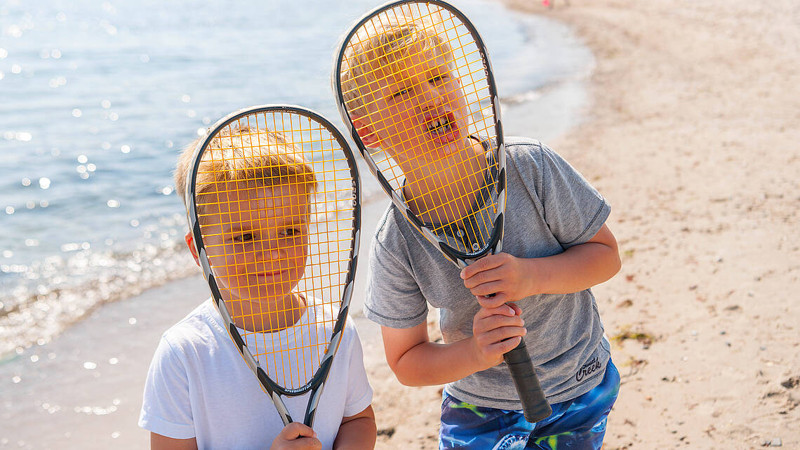 Zwei Jungs spielen Federball am Strand
