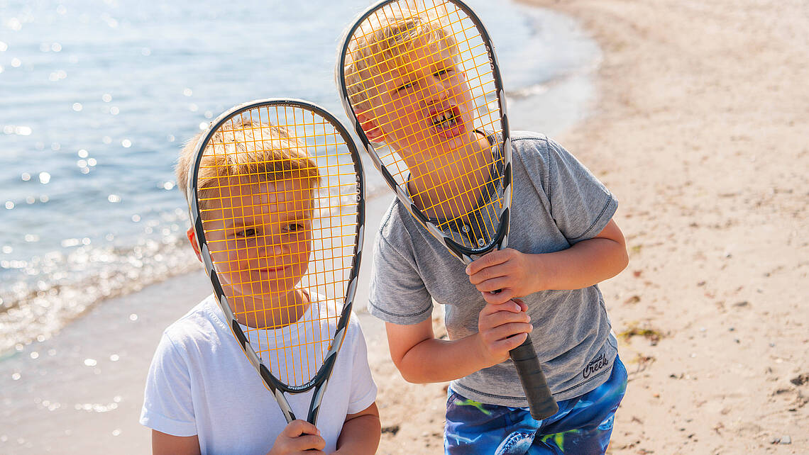 Zwei Jungs spielen Federball am Strand