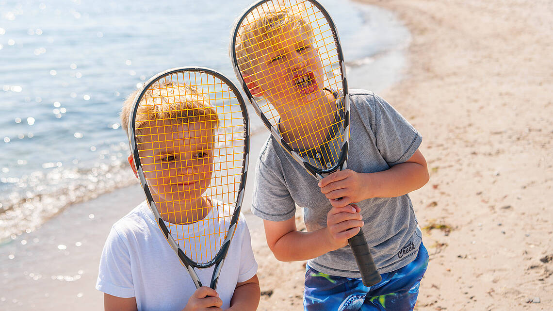 Zwei Jungs spielen Federball am Strand