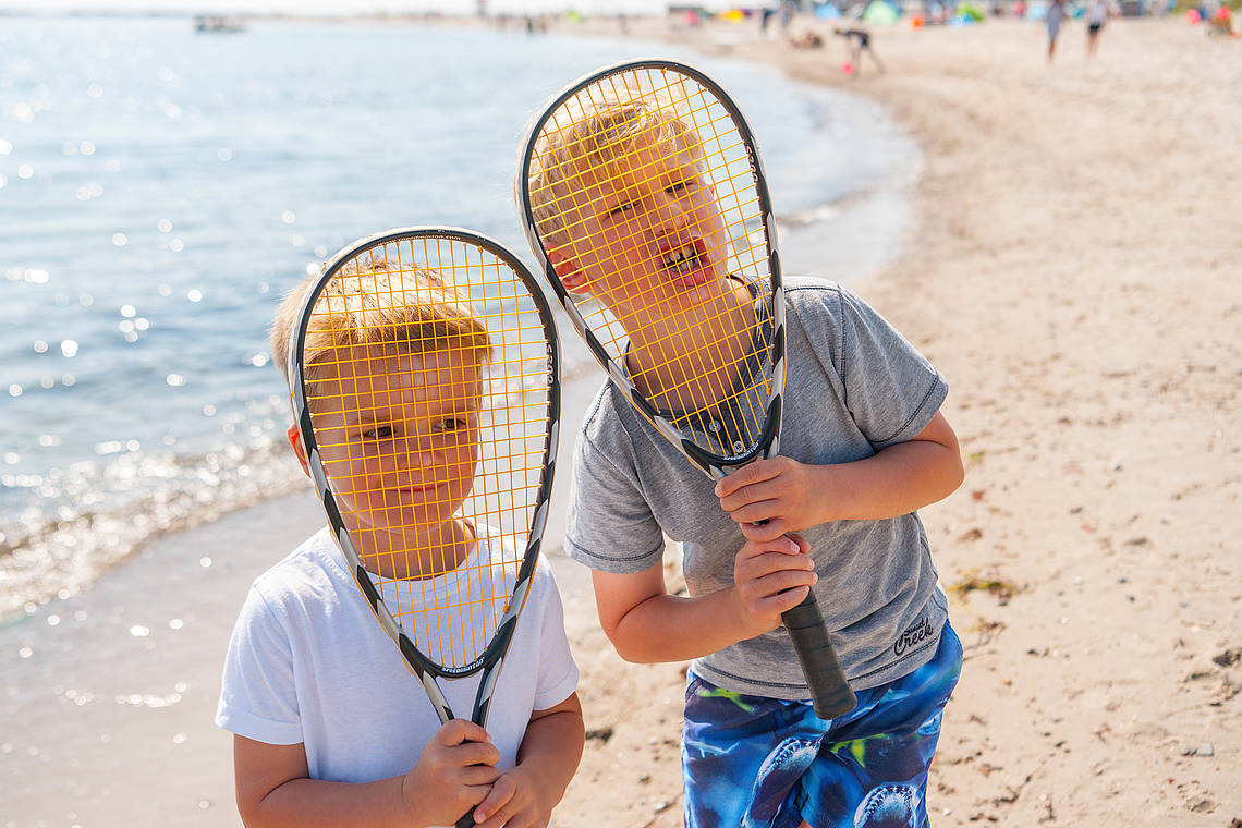 Zwei Jungs spielen Federball am Strand
