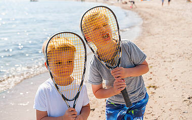 Zwei Jungs spielen Federball am Strand