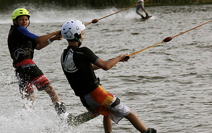 Wasserski in Dampland Zwei Personen fahren Wasserski