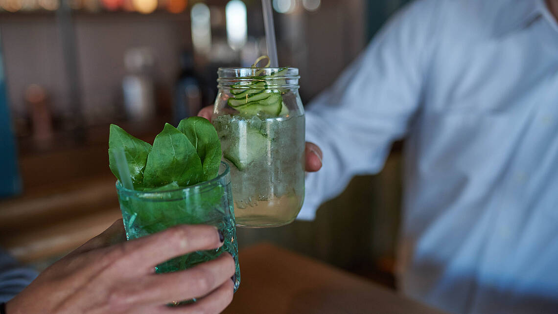 Zwei Menschen stoßen mit Ihren Cocktails an