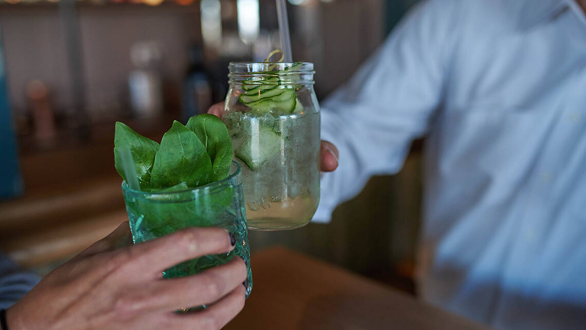 Zwei Menschen stoßen mit Ihren Cocktails an