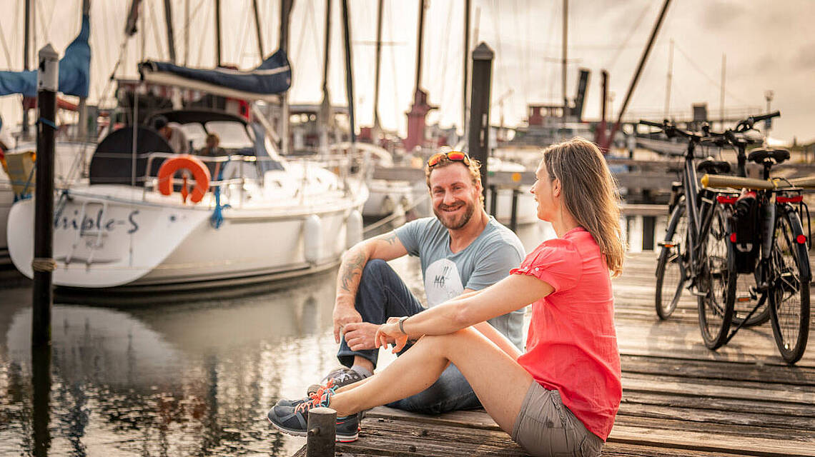 Pärchen sitzt auf den Steg des Yachthafens