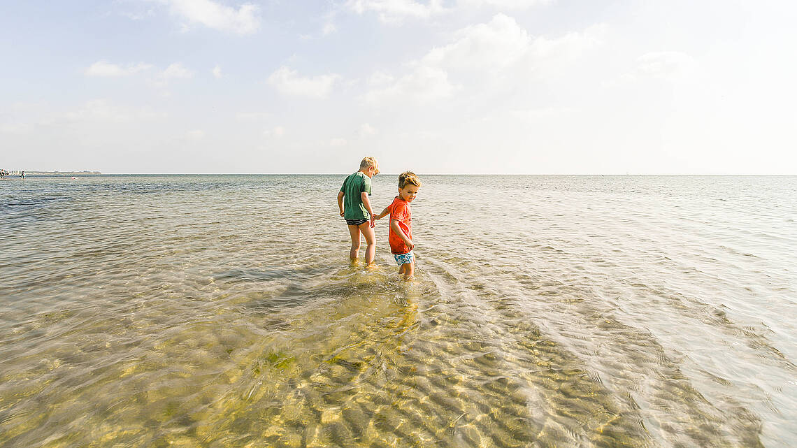 Kinder waten durchs flache Wasser