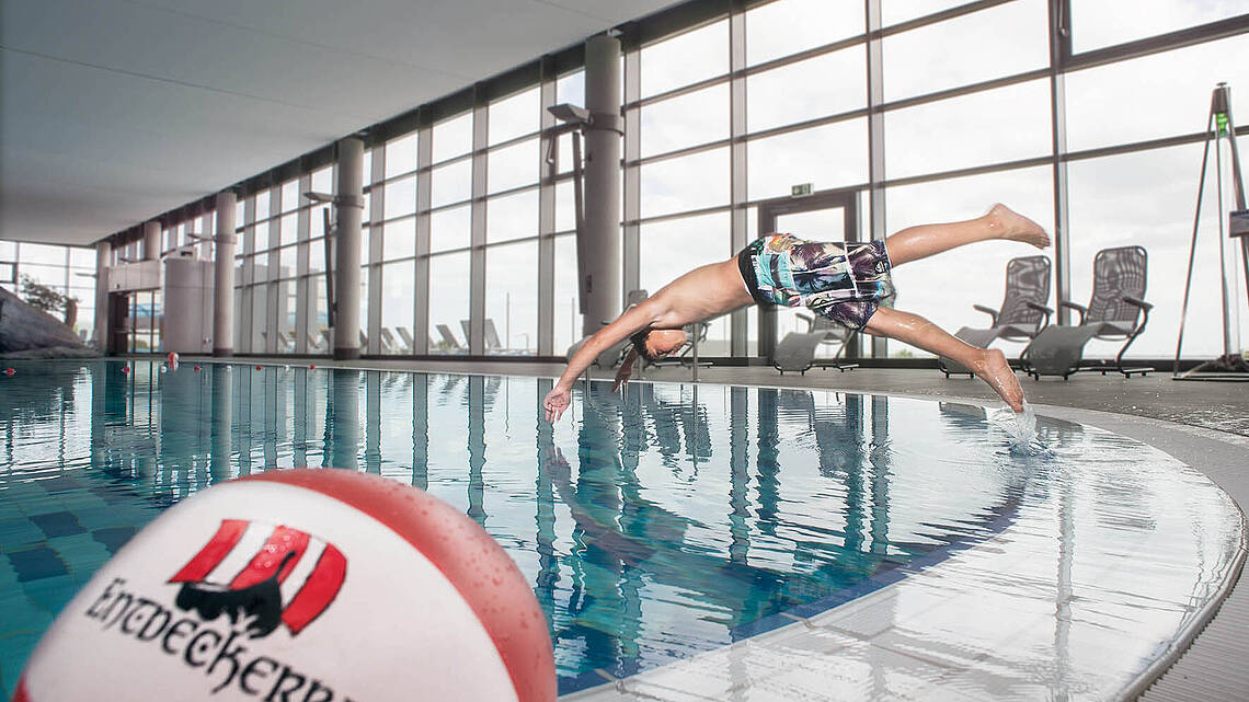 Ein Junge springt kopfüber vom Beckenrand in den Pool