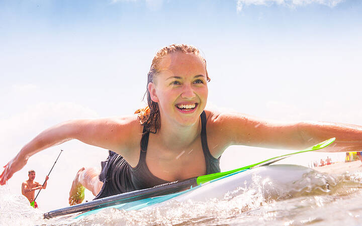 SUPen im Ostsee Resort Dampland Glückliche Frau paddelt auf ihrem Surfbord