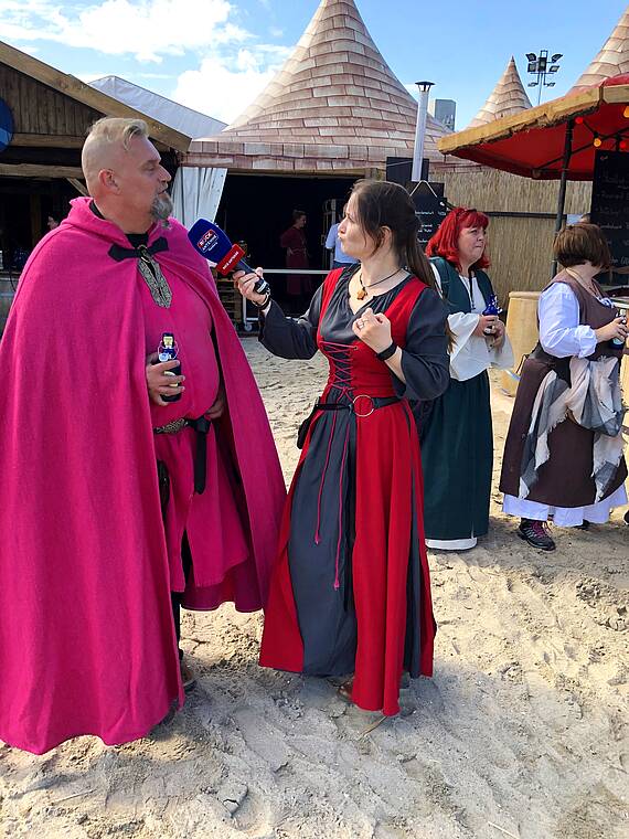 Eine Reporterin interviewt einen Schausteller am Strand
