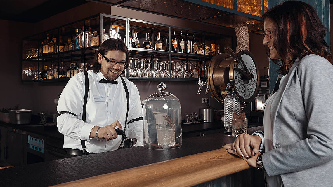 Barkeeper mixt einem Gast einen Cocktail