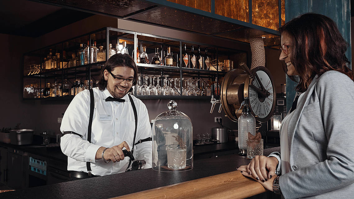 Barkeeper mixt einem Gast einen Cocktail